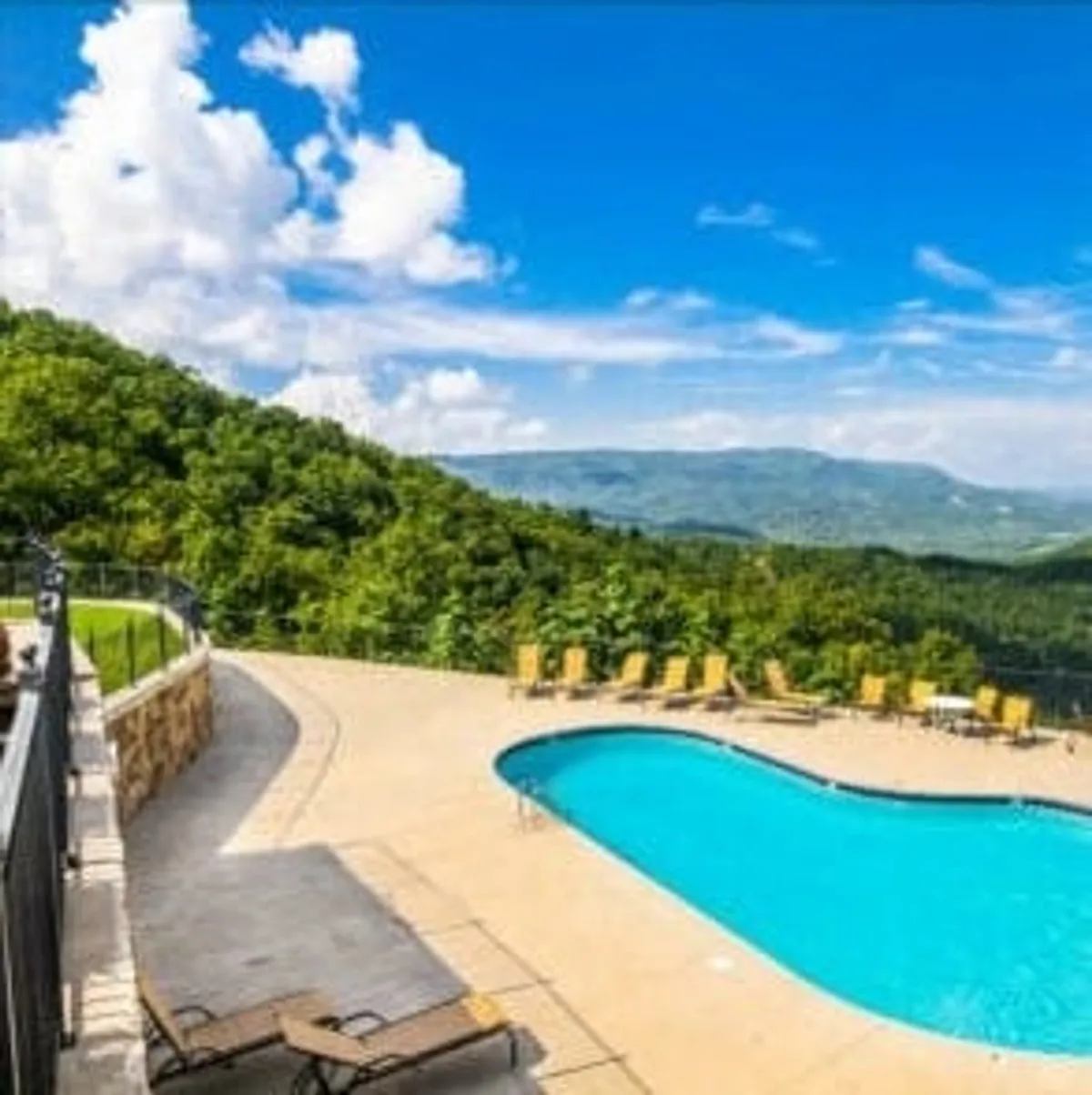 A stunning outdoor swimming pool set against a backdrop of mountain views and lined with lounge chairs. The scene captures both the fun and relaxation of a resort experience, inviting families to swim, sunbathe, or simply take in the scenery.