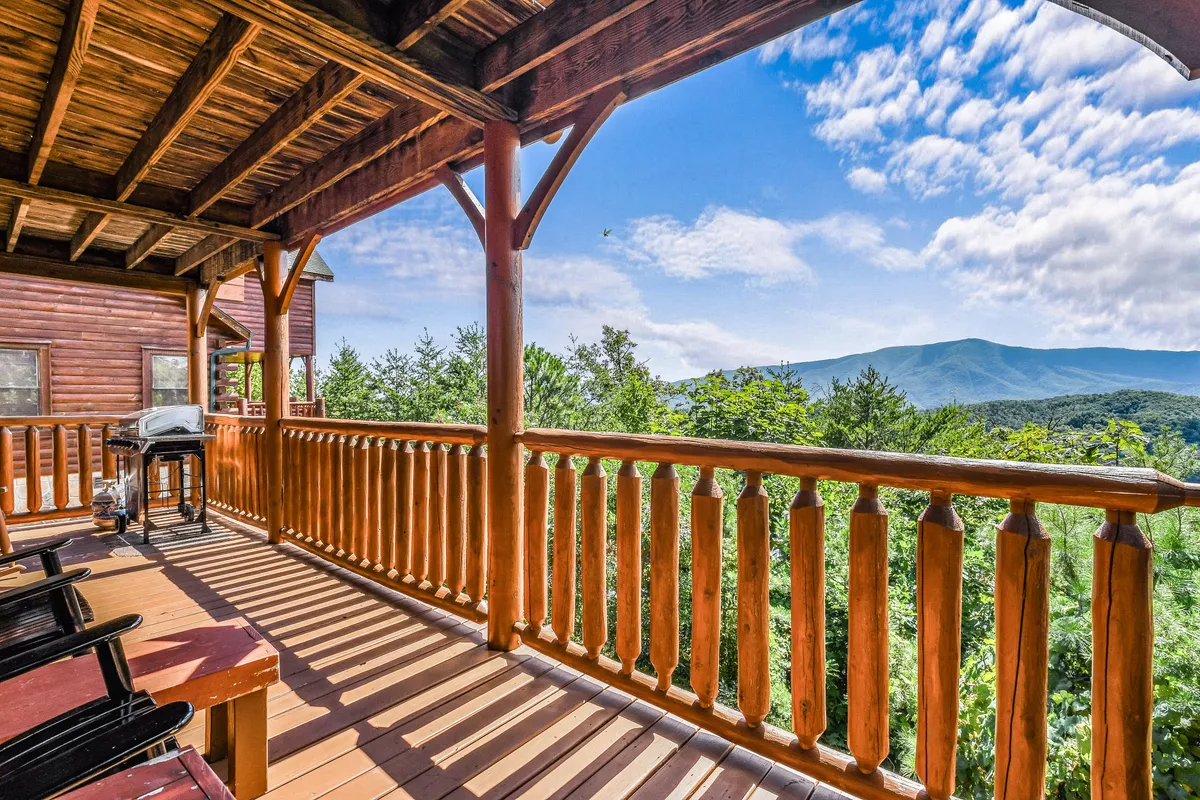 A spacious outdoor deck featuring comfortable seating and a grill, positioned to take in beautiful mountain views. The wooden railing and inviting setup create an ideal spot for barbecues, family meals, or simply enjoying the mountain air with loved ones.