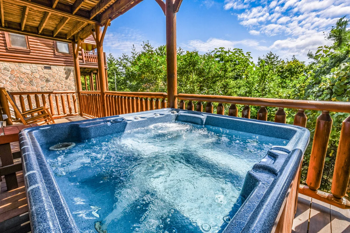 A tranquil deck scene with a bubbling hot tub, wooden railings, and a scenic nature view. The hot tub is the focal point, inviting guests to unwind while enjoying the fresh air and surroundings—perfect for relaxing after a round of games.